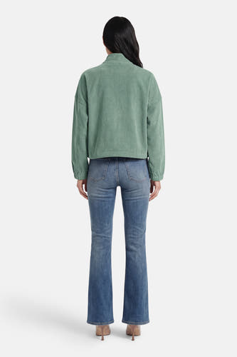 Veste courte verte de ONLY, à manches longues et portée avec un jean bleu et des talons.