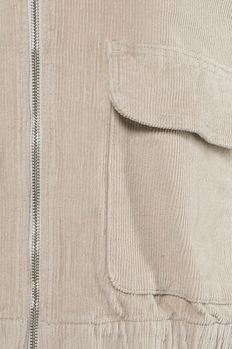 Manteau écru de ONLY, avec une texture côtelée et une fermeture éclair argentée, détail de poche visible.
