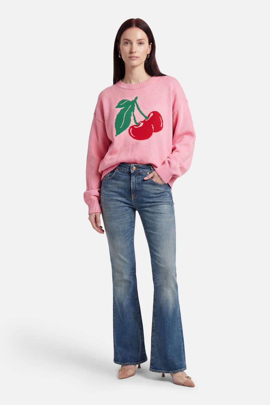 Roze trui met ronde hals van ONLY, met kersenprint op de voorkant, gecombineerd met jeans en pumps.

