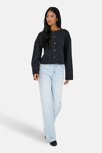 Grijze cardigan van ONLY, gedragen met lichtblauwe jeans met wijde pijpen en zwarte schoenen.