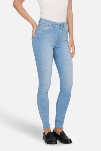 Jean skinny bleu clair ONLY, associé à un top sans manches et des chaussures noires.