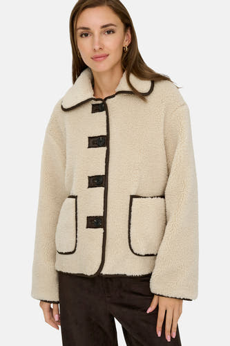 Mauve court manteau de JDY, avec des accents bruns sur les boutons et les poches, porté sur un pantalon brun.