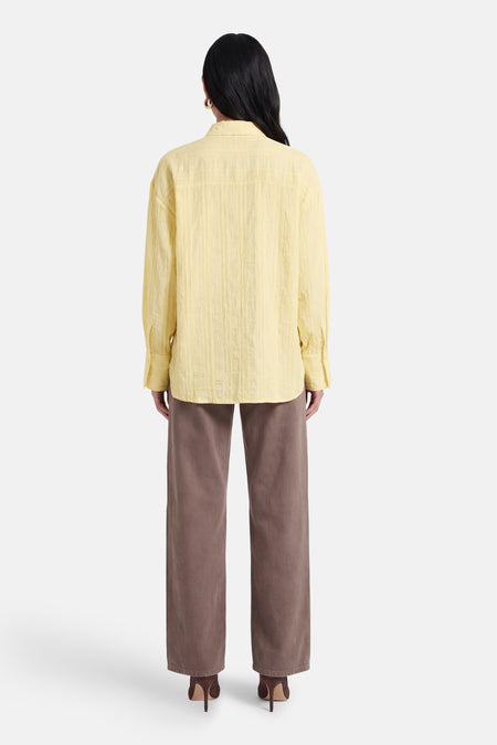 Chemise jaune à manches longues de JDY, avec texture, portée avec un pantalon marron et des talons, vue arrière.
