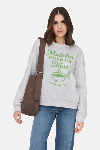 Pull gris ONLY®, avec un imprimé vert et porté avec un jean et des bottes noires.