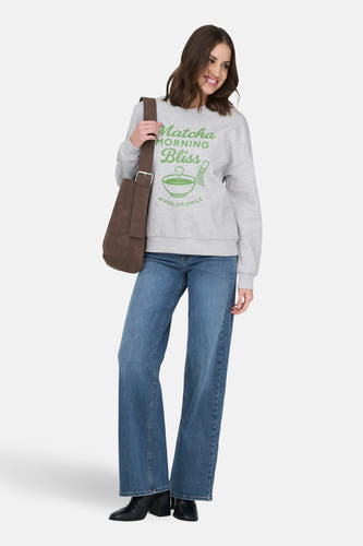 Grijze sweater van ONLY®, met een groene opdruk en gedragen met jeans en zwarte laarzen.