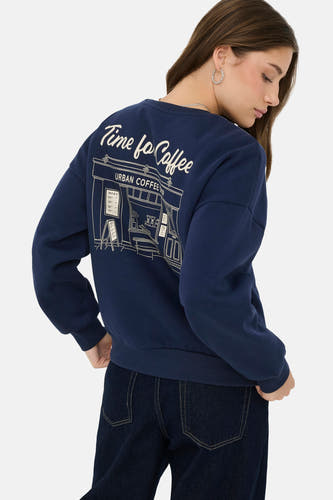 Pull bleu d'ONLY avec imprimé d'un café dans le dos, combiné avec un jean foncé.