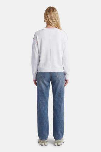 Pull blanc à col rond de JDY, avec détails roses le long de l'épaule et jean droit.