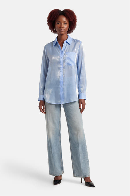 Blauw hemd met lange mouwen van ONLY®, met glanzende textuur, gedragen met wijde jeans en zwarte hakken.
