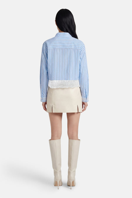 Chemise bleue rayée à manches longues ONLY®, finie avec des détails en dentelle, combinée avec une jupe écru et des bottes.