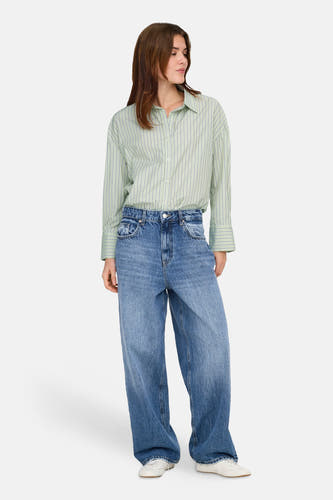 Groen hemd met lange mouwen van ONLY, met verticale strepen, gedragen met wijde jeans en witte sneakers.
