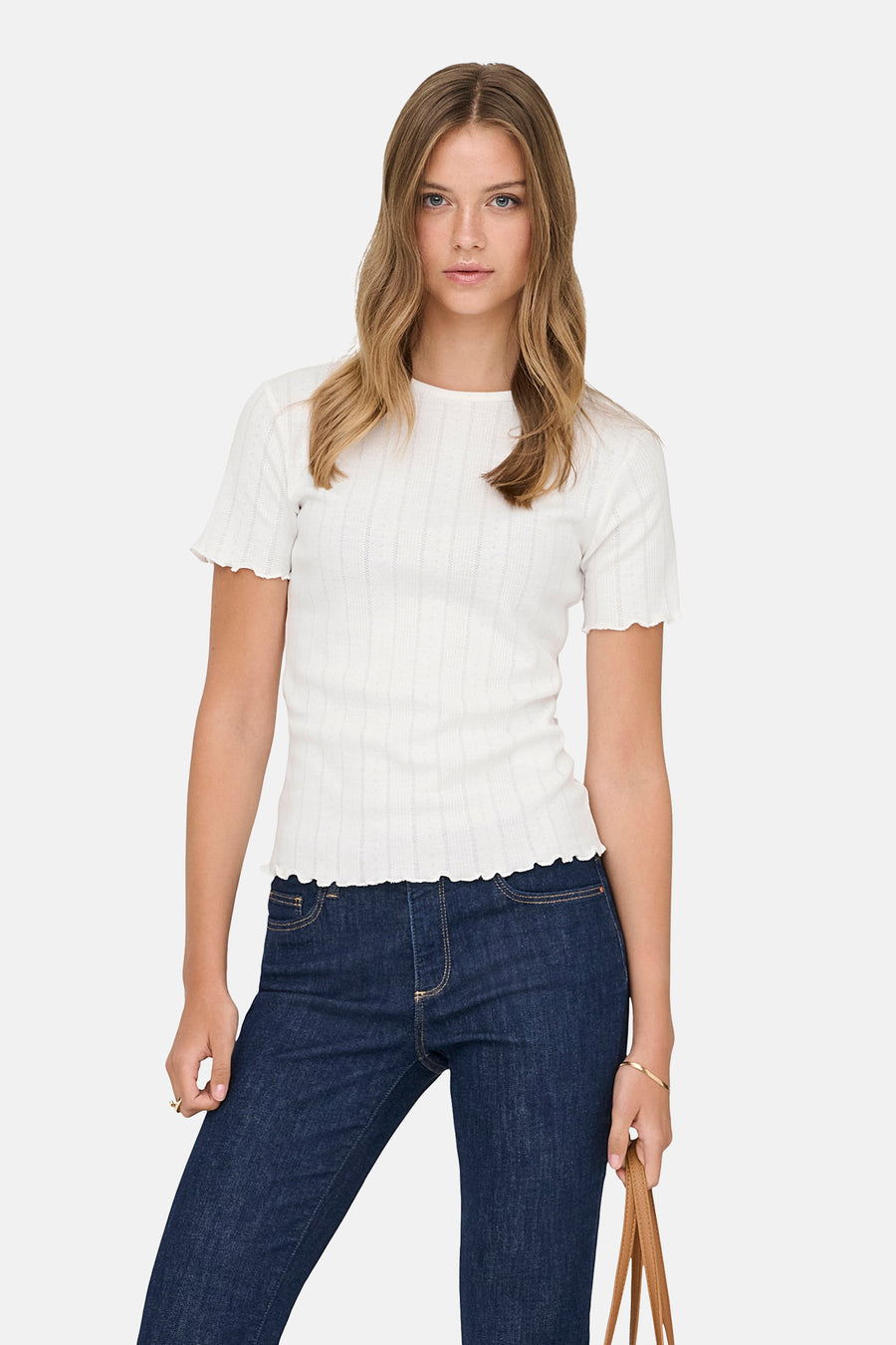 T-shirt blanc à manches courtes ONLY, avec côtes et ourlet ondulé à l'ourlet, combiné avec un jean foncé.
