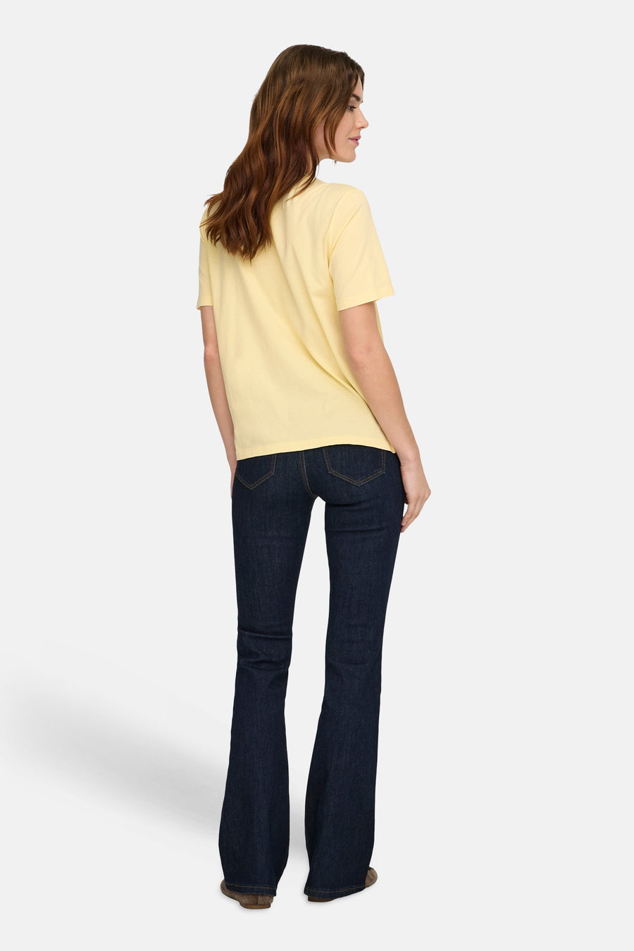 T-shirt à manches courtes jaune de ONLY®, dos d'une femme en jean flare foncé.