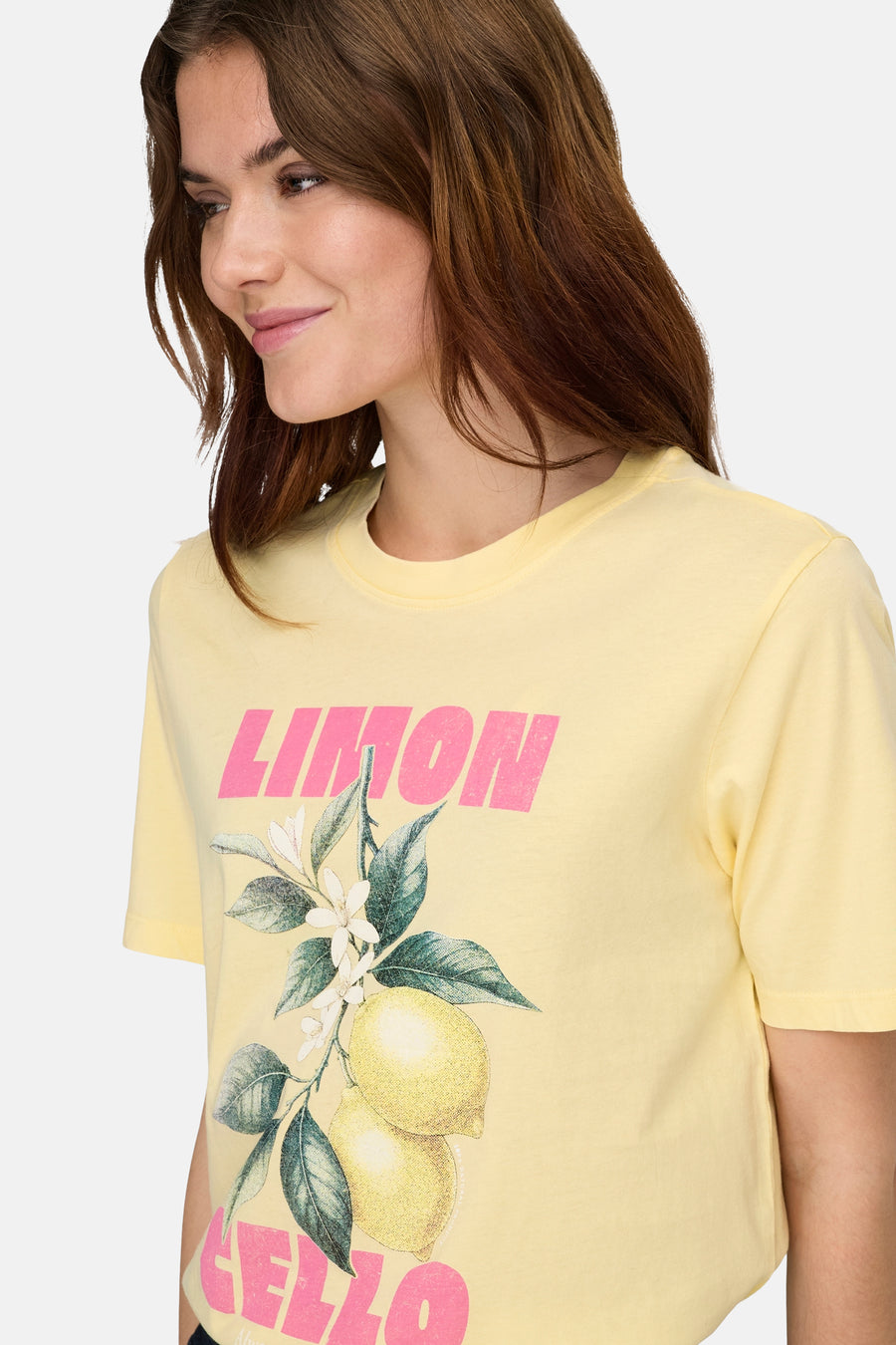 T-shirt jaune de ONLY® avec texte rose 'LIMON' et imprimé citron, porté par une femme souriante.