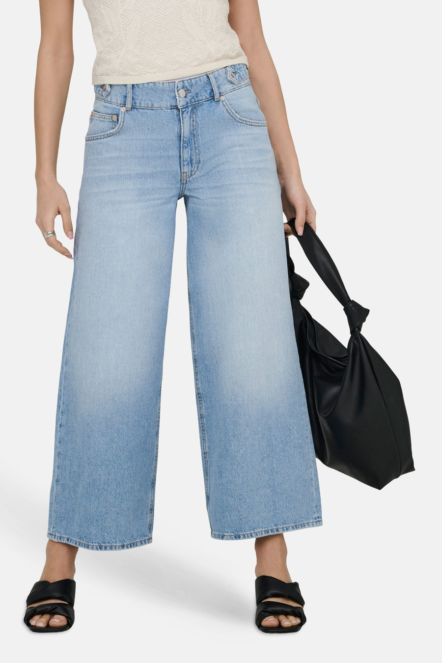 Jeans taille haute en denim bleu clair de ONLY, avec jambes larges et portées avec un haut en maille et des sandales noires.