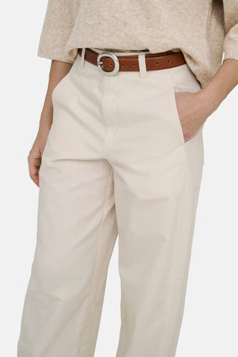 Pantalon écru de JDY avec une ceinture marron et une main dans la poche.