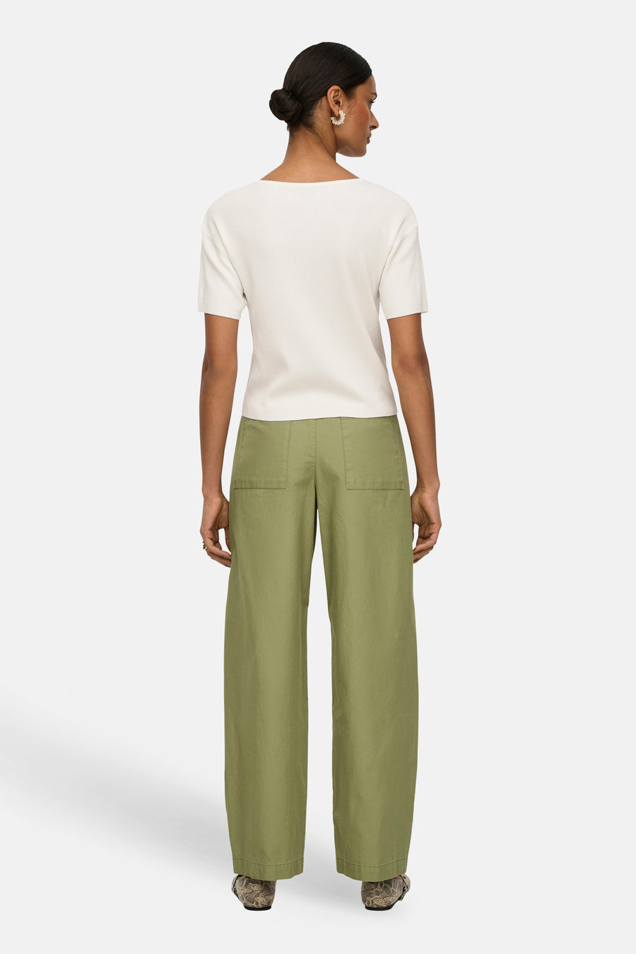 Groene broek van JDY met wijde pijpen en achterzakken, gecombineerd met een crèmekleurige top en opvallende schoenen.