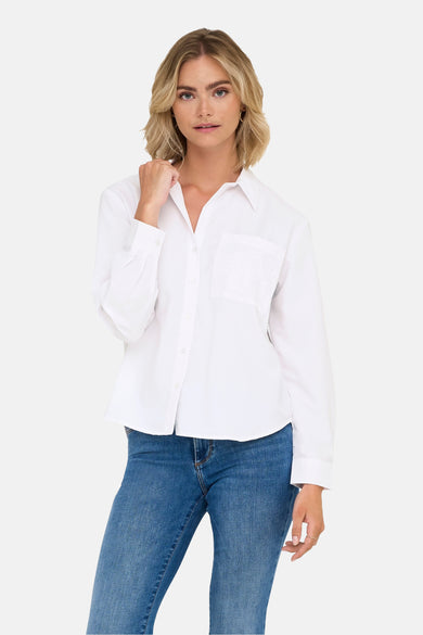 Chemise blanche à manches longues de JDY, avec une poche po po et portée avec des jeans bleus.