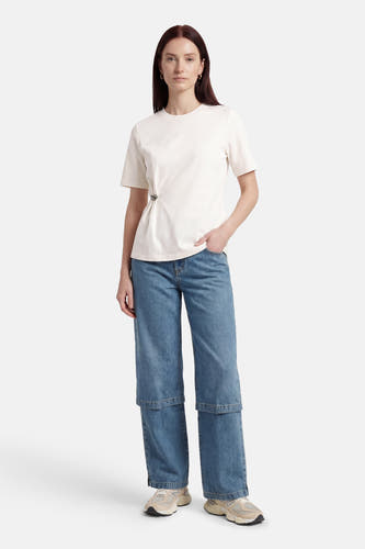 T-shirt blanc à manches courtes ONLY, avec une épingle décorative sur le côté et associé à un jean ample.