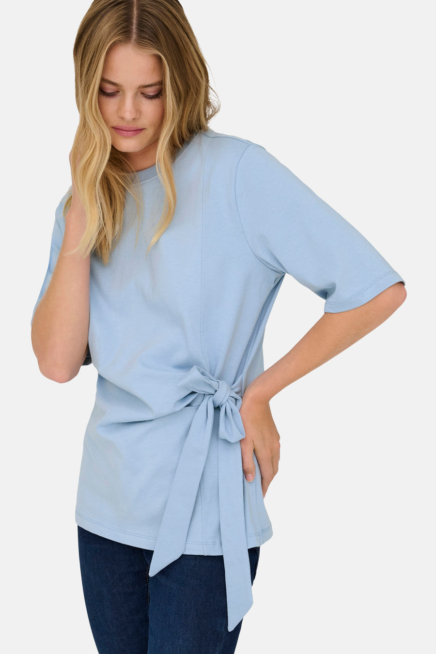 T-shirt bleu à manches courtes de ONLY, avec détail de bouton sur le côté et porté avec un jean foncé.