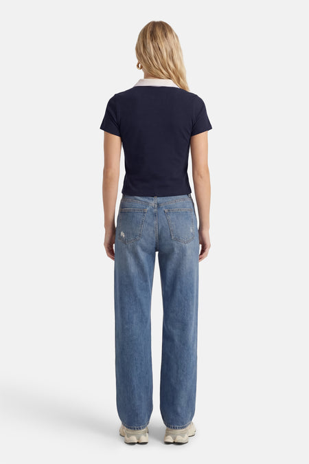 Polo bleu à manches courtes de ONLY®, vue de dos, avec un col blanc et associée à un jean.