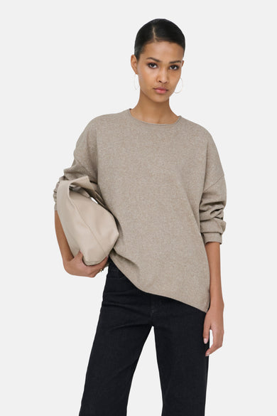 Pull beige avec col rond de ONLY, avec des manches longues et associé à des jeans noirs et des baskets rouges.