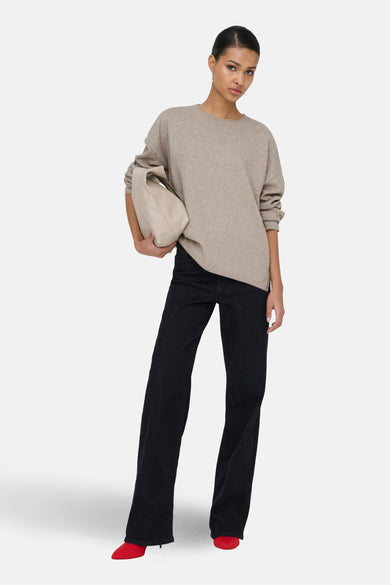 Beige trui met ronde hals van ONLY, met lange mouwen en gecombineerd met zwarte jeans en rode hakken.
