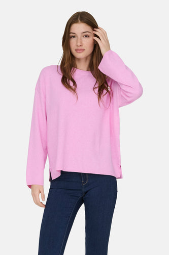 Vrouw in roze trui en blauwe jeans.