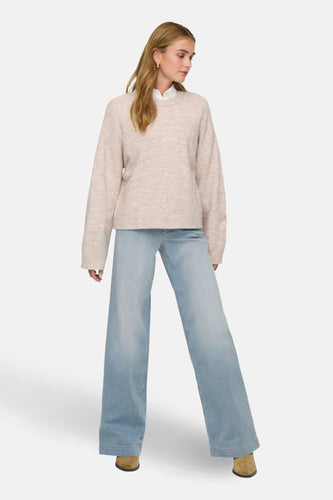 Vrouw in lichte trui en wijde jeans.