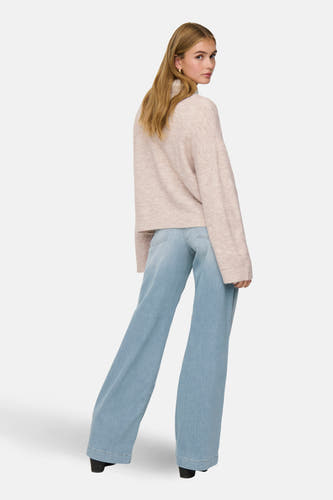 Gilet rond beige de ONLY, avec des manches longues et porté avec des jeans larges et des chaussures noires.