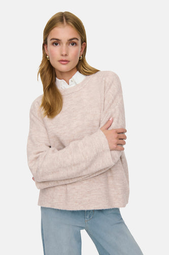 Vrouw met beige trui en blauwe jeans.