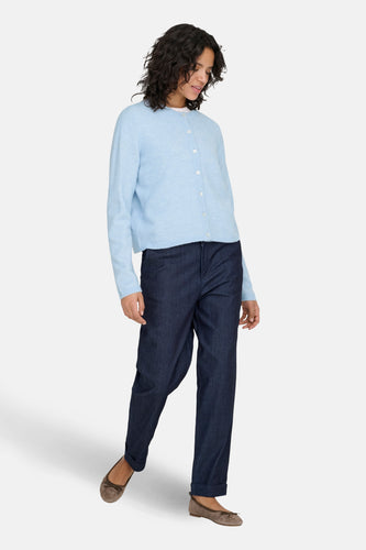 Vrouw in blauw vest en donkere broek, suède ballerina's.