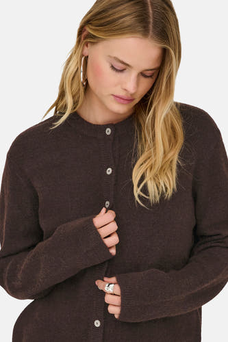 Veste brune ONLY, avec fermeture à boutons et longues manches, portée avec des boucles d'oreilles et un anneau en argent.