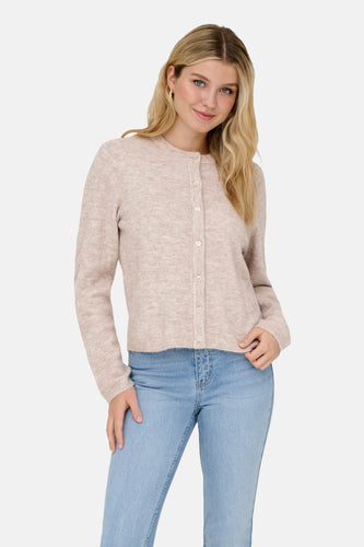 Een vrouw in een beige cardigan en blauwe jeans.