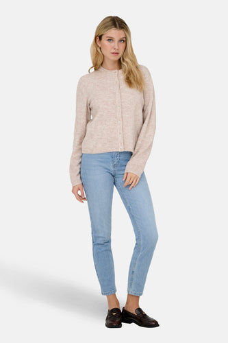 Vrouw, lichtroze vest, jeans, leren loafers, staand.