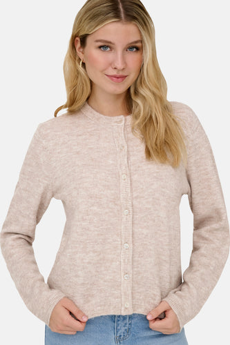 Vrouw met blond haar in een beige vest van gebreide stof.