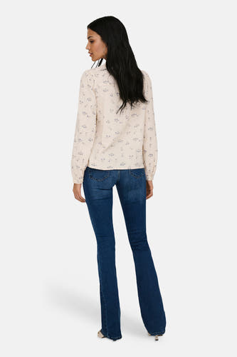 Chemise écru à manches longues ONLY®, avec un motif floral délicat, portée avec un jean évasé.