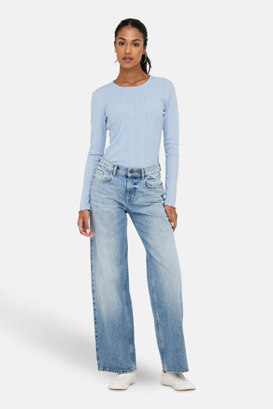 T-shirt bleu à manches longues de ONLY, avec une structure en côtes, associé à des jeans larges et des baskets blanches.