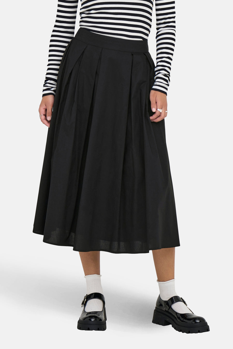 Jupe longue noire ONLY, avec des plis et une longueur midi, portée avec un haut rayé et des chaussures noires.