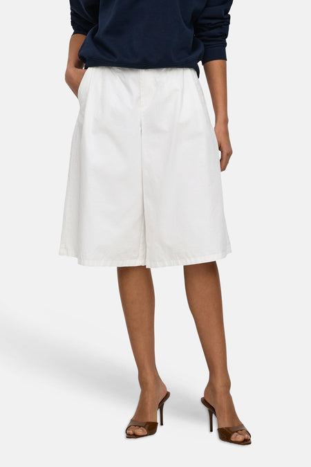 Short blanc JDY à coupe ample et tissu légèrement froissé, porté par un mannequin avec un pull bleu marine et des talons marron.