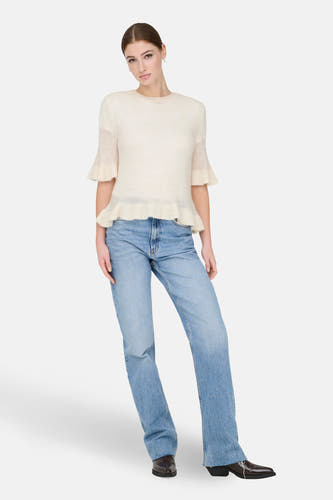 Ecru trui van ONLY®, met korte mouwen en een geplooide zoom, gecombineerd met een blauwe jeans en zwarte schoenen.

