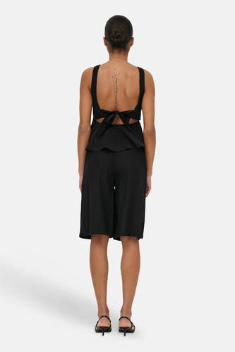 Haut noir sans manches ONLY® avec détail de nœud au dos et ourlet péplum, porté avec un short noir.