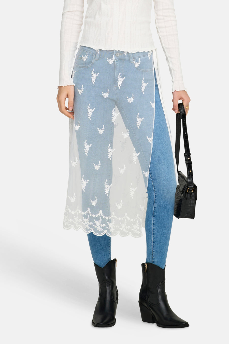 Witte rok van ONLY, met kanten details, gedragen over een blauwe jeans met bloemenborduursel en zwarte laarzen.