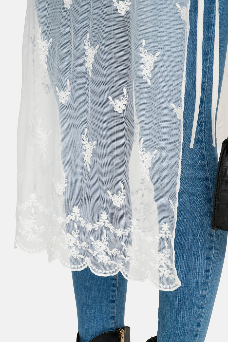 Jupe blanche ONLY, avec un motif floral en dentelle et un ourlet ondulé, portée sur un jean.