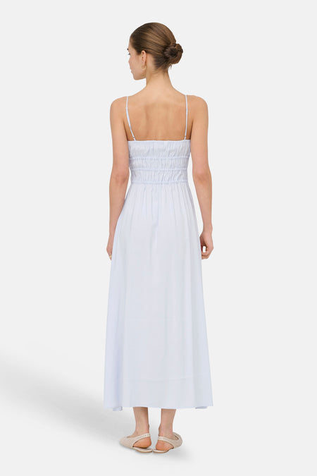 Robe bleu clair sans manches ONLY® avec fines bretelles et taille froncée, vue arrière portée par un mannequin avec boucles d'oreilles dorées et sandales beiges.