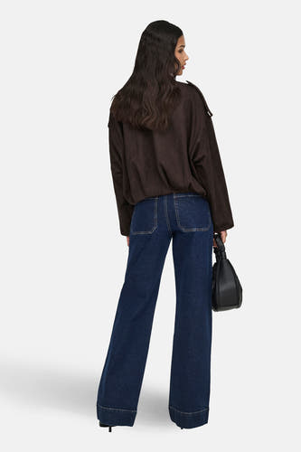 Manteau court brun de JDY avec des détails sur les épaules, associé à des jeans foncés larges et une sac noir.