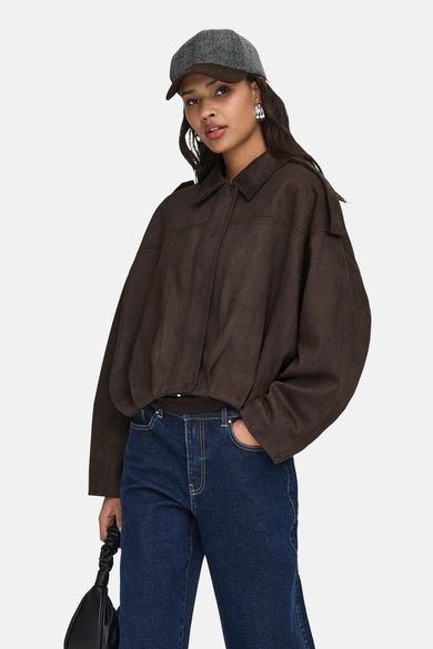 Manteau court brun de JDY, avec col et porté avec un chapeau et des jeans.