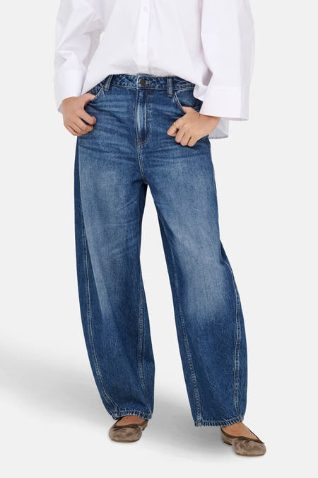 Jean en denim bleu marine spécial fit de JDY, porté avec un chemisier blanc et des ballerines brunes.