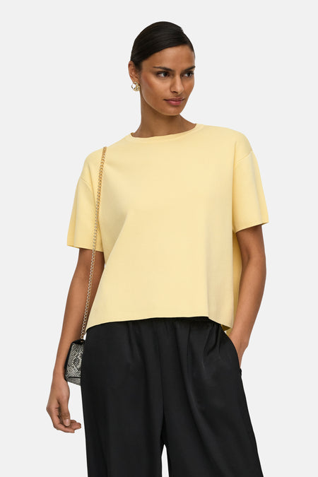 Pull jaune à col rond de JDY, porté avec un pantalon noir ample et des ballerines en cuir de serpent.