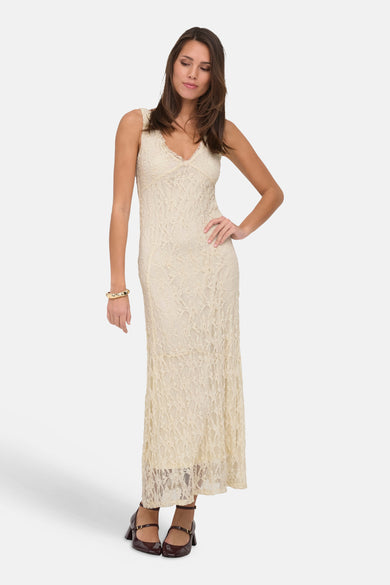 Robe longue sans manches écru d'ONLY® avec texture en dentelle et col en V, portée par un mannequin avec des chaussures marron et un bracelet doré.