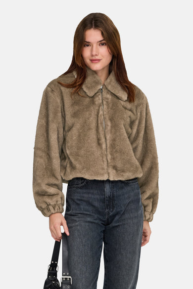 Vrouw met bruine jas en donkere jeans.